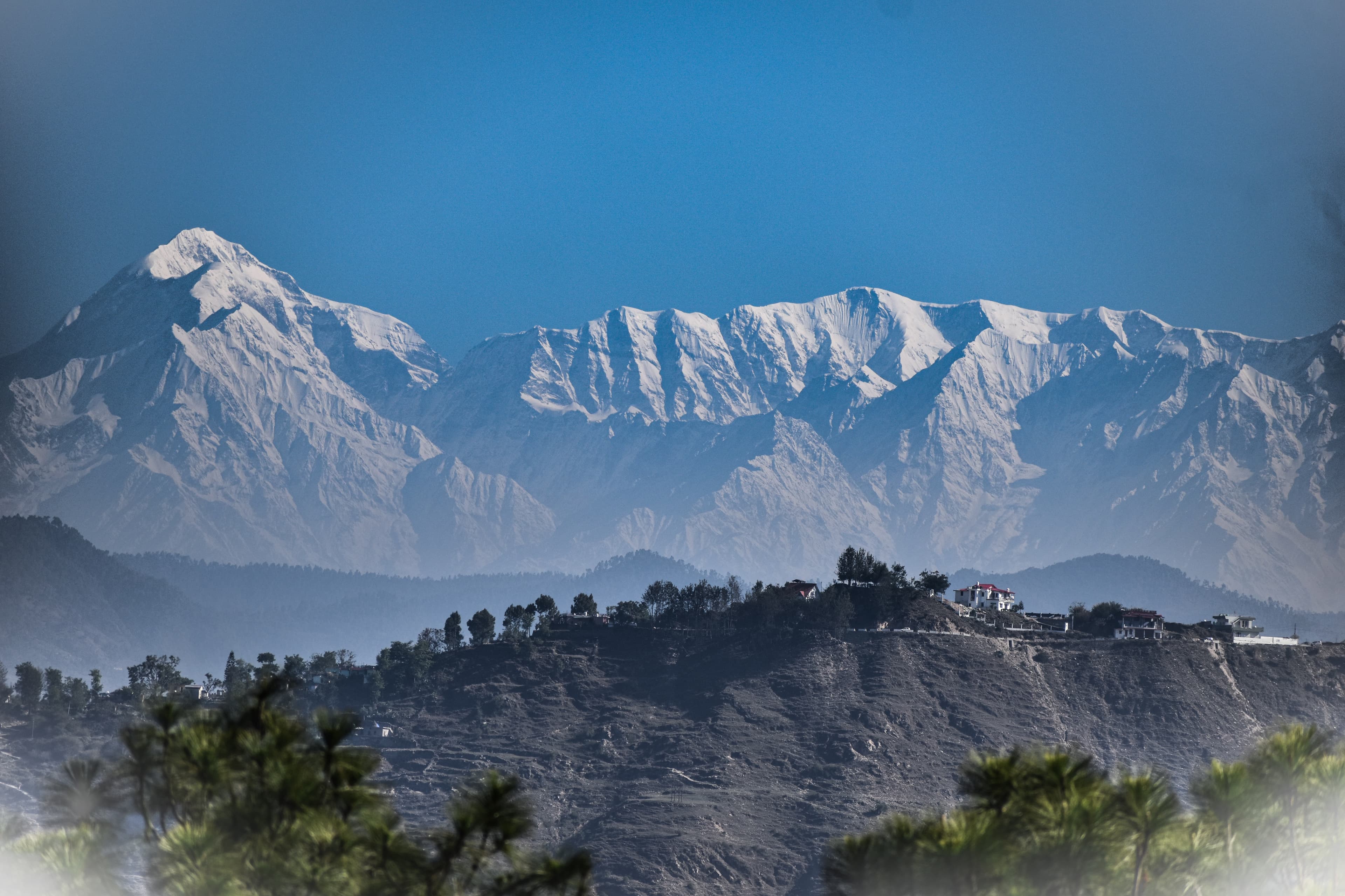 View of the majestic Himalayas during sunrise, with snow-capped peaks and a clear blue sky